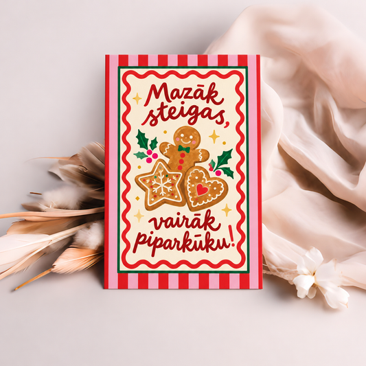 Ziemassvētku kartīte ar piparkūku ilustrācijām, rozā un sarkanu svītrainu apmali un uzrakstu “Mazāk steigas, vairāk piparkūku!”.