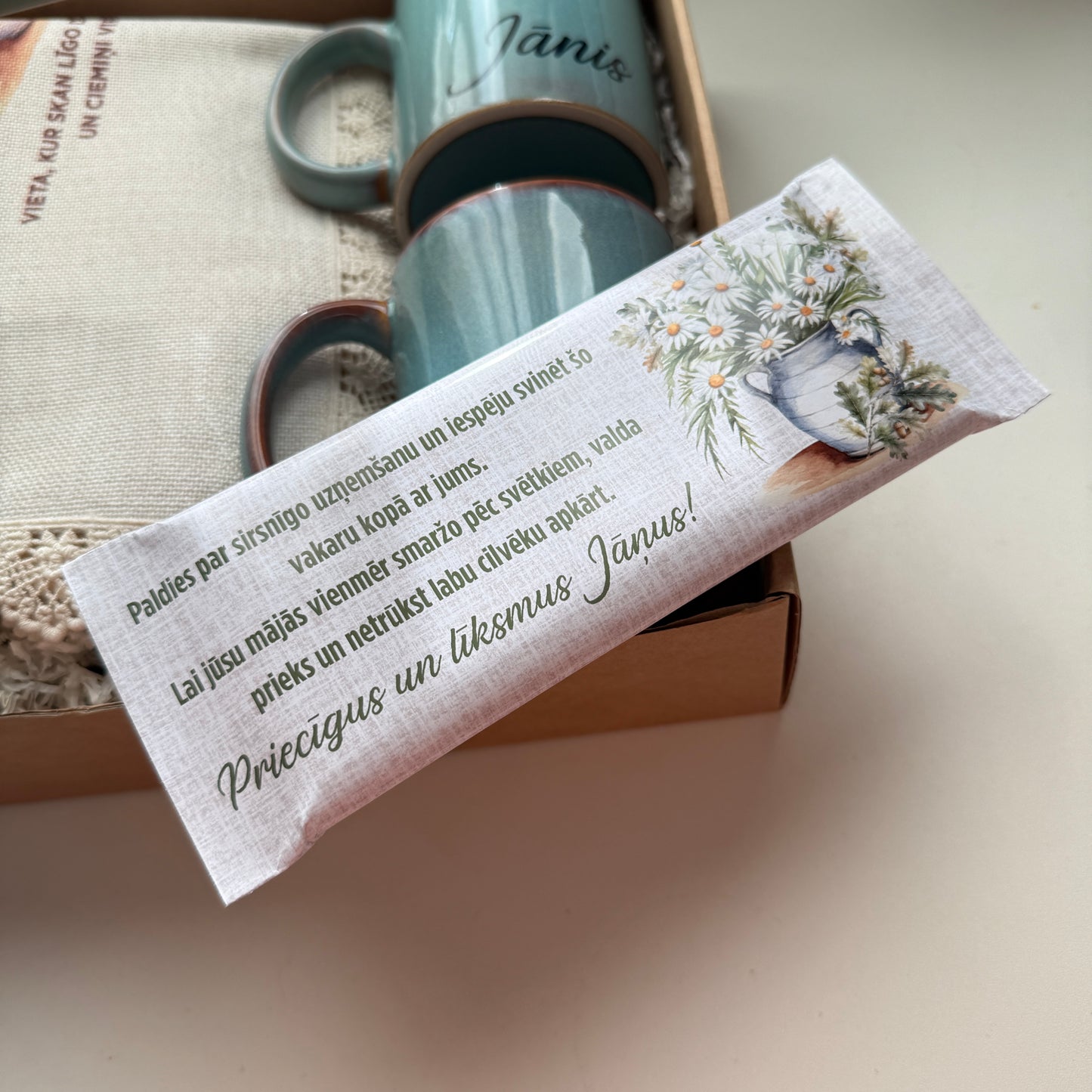 Jāņu dāvanu komplekts ar divām keramikas krūzēm, personalizētu šokolādi un galdautiņu pļavas stilā kastītē | Zelta Pūka